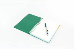 Open green book with pen on white background.